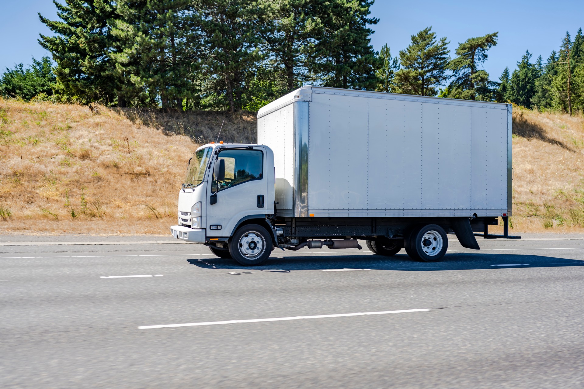 Compact small cab over rig semi truck with box trailer running on the highway for local delivery